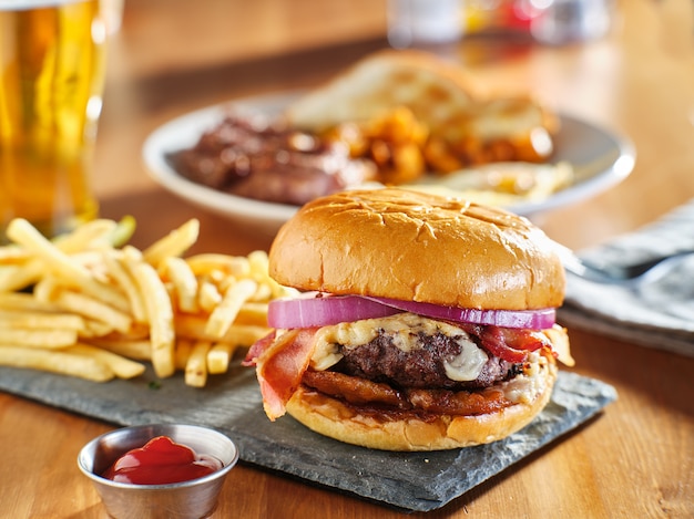 Speckburger nach westlicher Art mit Zwiebelringen und Bbq-Sauce