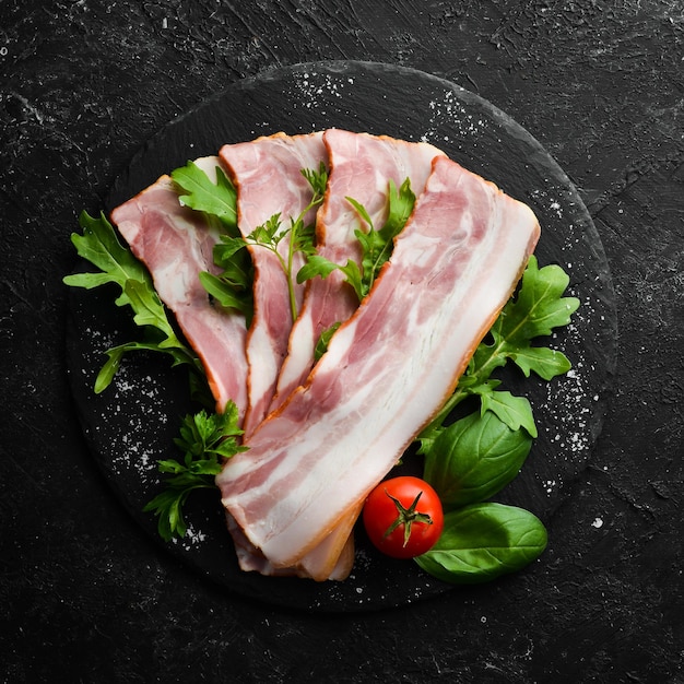 Speckscheiben mit Rucola und Petersilie auf einem schwarzen Teller Draufsicht Freier Platz für Ihren Text