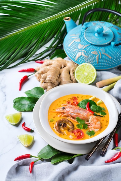 Speisen und Getränke, traditionelle thailändische Küche. Würzige tom yam kung, tom yum sour suppe mit garnelen, garnelen, kokosmilch, zitronengras und chilipfeffer in einer schüssel auf einem weißen tisch