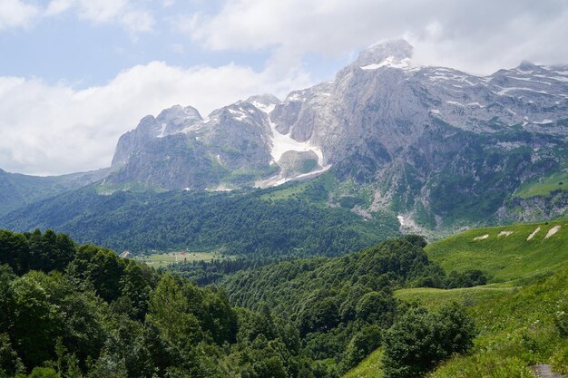 Spektakuläre Berglandschaft mit grünen Wäldern und schneebedeckten Gipfeln