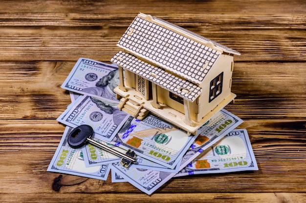 Sperrholzmodell des Hauses, des Schlüssels und der 100-Dollar-Banknoten. Darlehen, Immobilienkonzept