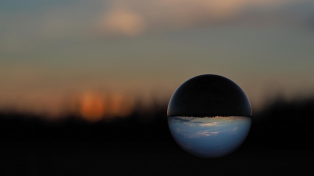 Sphärische Linse (Kristallkugel) und farbenfroher Sonnenuntergang vor dem Hintergrund des Waldes.