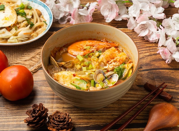 Spicy Hot Pot Noodles mit Tomate und Essstäbchen, serviert in Teller auf Holztisch mit Blick auf chinesisches Essen