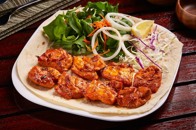 Spicy Sheesh Tawook ou shish tikka boti kebab com salada de limão e pão servido em prato isolado na vista lateral da mesa de comida do Oriente Médio