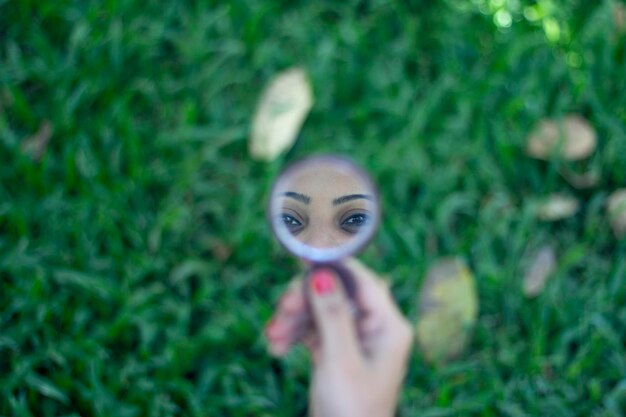 Foto spiegelbild einer frau im handspiegel auf pflanzen