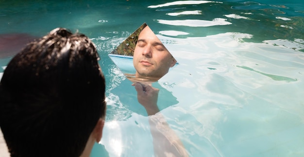 Foto spiegelbild eines mannes, der im schwimmbad sitzt