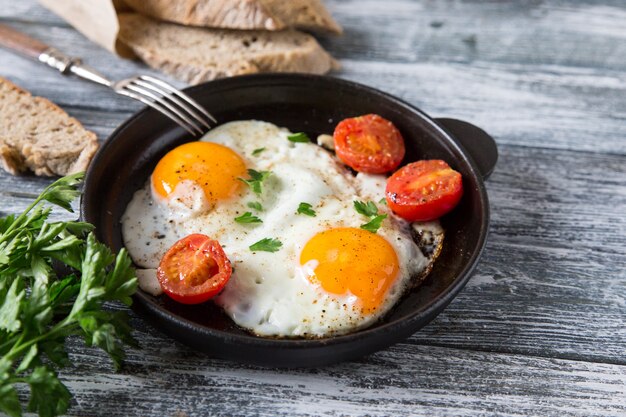 Spiegelei. Schließen Sie herauf Ansicht des Spiegelei auf einer Bratpfanne mit Kirschtomaten und Petersilie