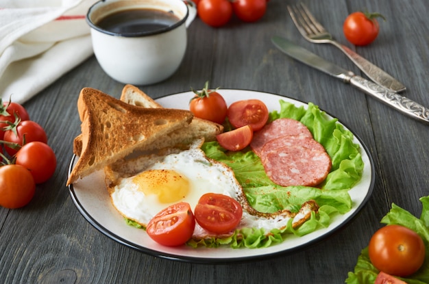 Spiegelei, Tomaten, Wurst, Brotscheiben und Salat auf einem Teller