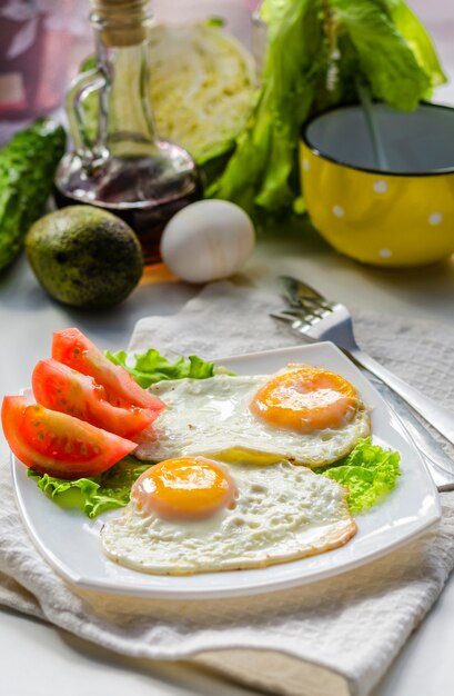 Spiegeleier aus zwei Eiern auf einem Teller mit Tomaten