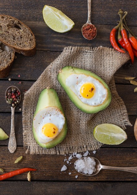 Spiegeleier in der avocado mit rotem pfeffer und verschiedenen gewürzen.