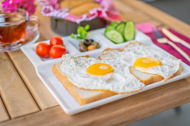 Spiegeleier mit der Sonnenseite nach oben auf Brot mit Beilagen. Frühstückskonzept