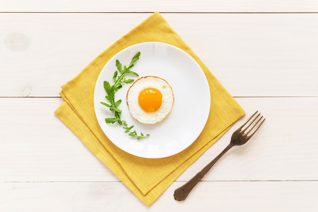 Spiegeleier mit Rucola in einem Teller auf einer gelben Leinenserviette