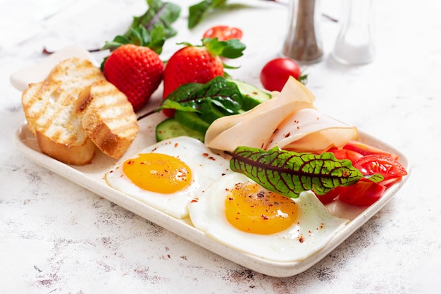 Spiegeleier mit Schinken, Tomaten, Gurken, Erdbeeren und Toast Delicious English Breakfast Brunch