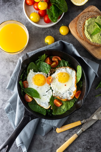 Spiegeleier mit Spinat, Avocado-Toast und frischen Tomaten, gesunde Frühstücksnahrung,