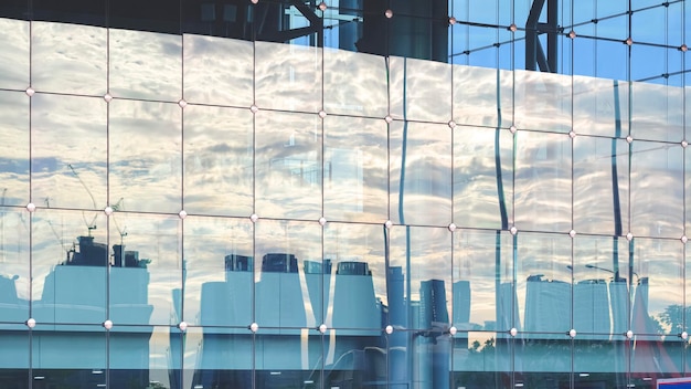 Spiegelung der Stadtansicht mit bewölktem Himmel auf der Oberfläche einer modernen Glasgebäudewand