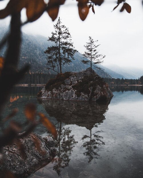 Spiegelung von Bäumen und Felsen im See gegen den Himmel im Winter