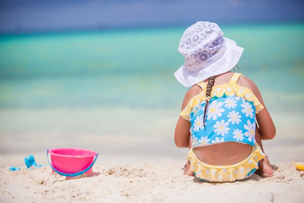 Spiel des kleinen Mädchens mit Strandspielwaren während der tropischen Ferien