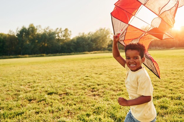 Spielen mit Drachen Afroamerikanische Kinder haben tagsüber im Sommer Spaß auf dem Feld
