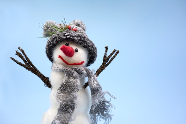 Spielen sie schneemann auf einem blauen hintergrund mit grauer strickmütze und grauem schal