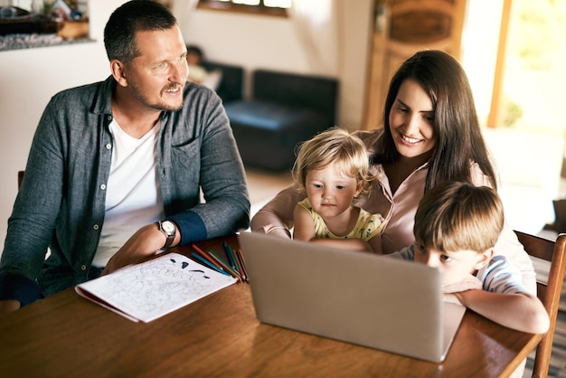 Spielen Sie Unterhaltung und lernen Sie alles in einem Schuss eines entzückenden Bruders und einer Schwester, die mit ihrer Mutter zu Hause einen Laptop benutzen