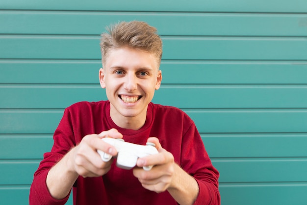 Spieler mit einem Gamepad in den Händen spielt eine Konsole auf Türkis