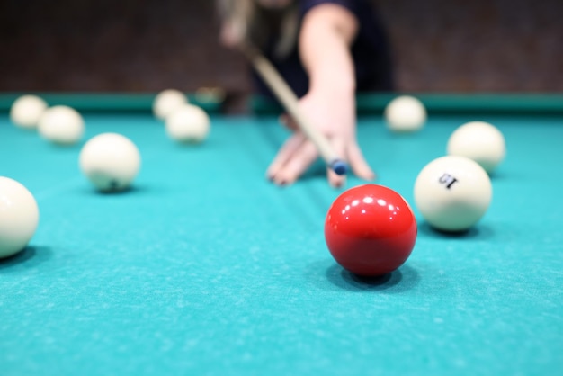 Spielerin bereit, roten Ball auf blauem Billardtisch zu schlagen Aktive Frau spielt gerne Billard