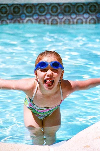 Spielhaftes Mädchen, das in einem Schwimmbad steht und die Zunge herausstreckt