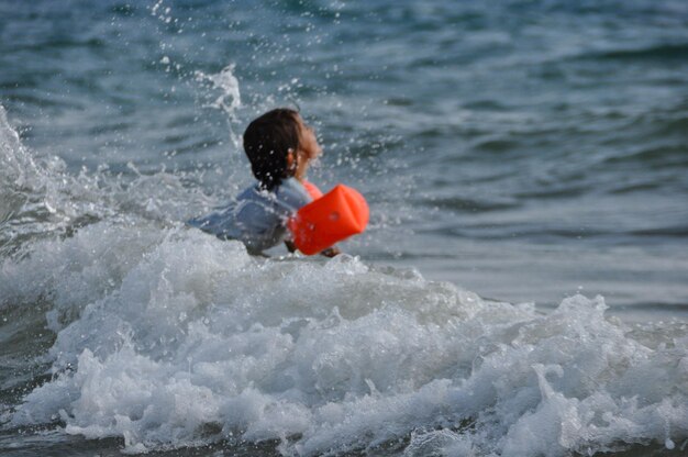 Foto spielhaftes mädchen mit eimer spielt am ufer am strand