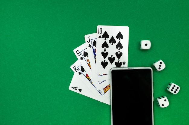 Spielkarten Pokerwürfel und Telefon auf grünblauem Tuch