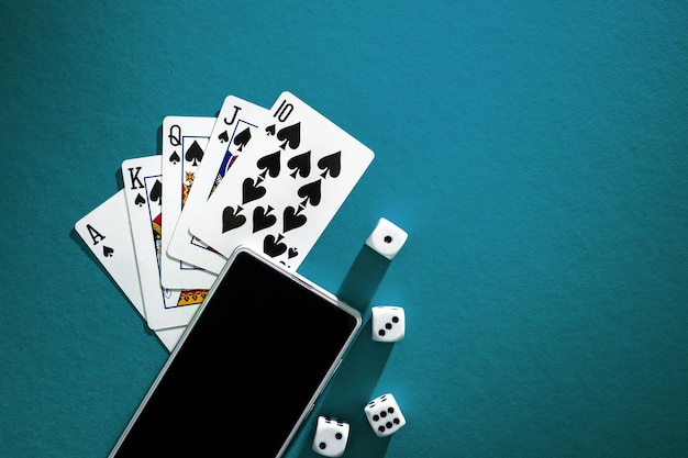 Spielkarten Pokerwürfel und Telefon auf grünblauem Tuch