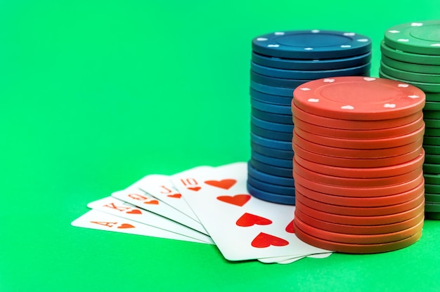 Spielkarten und Stapel von Pokerchips auf grünem Hintergrund