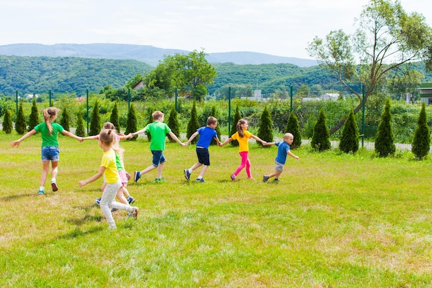 Foto spielschlange im freien. kinder laufen händchen haltend und sammeln sich gegenseitig ein