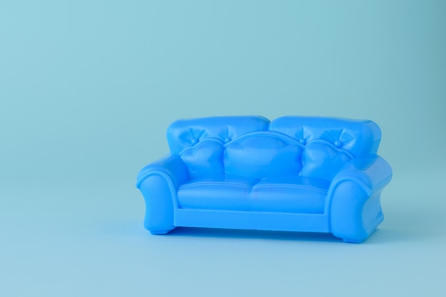 Spielzeug modernes blaues schönes Sofa auf einem blauen Hintergrund. Eine Probe von schönen Möbeln für das Haus. Minimalistisch.