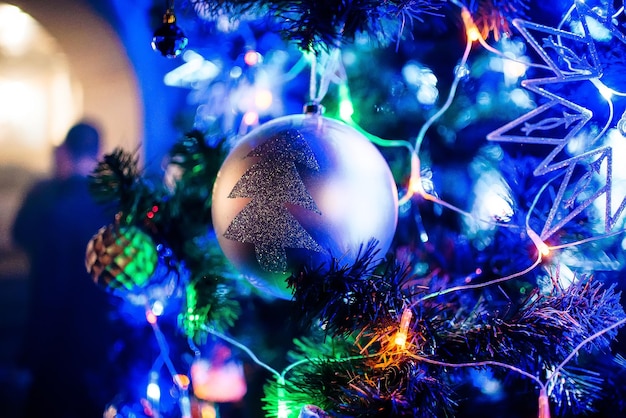 Spielzeugball auf Zweigen künstlicher Weihnachtsbaum mit verschwommenem Hintergrund der Lichtergirlande in der Nähe