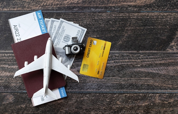 Spielzeugflugzeug, Flugticket, Kreditkarten, Dollar und Reisepass auf Holztisch. Reisekonzept