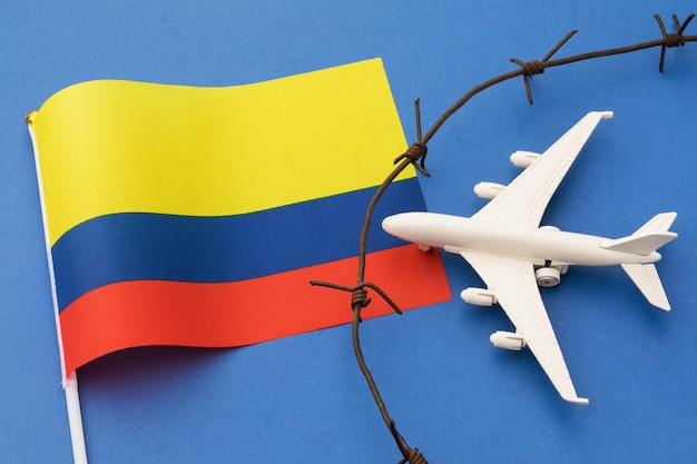 Spielzeugflugzeugflagge und Stacheldraht auf farbigem Hintergrund Kolumbien-Luftgrenzenverletzungskonzept