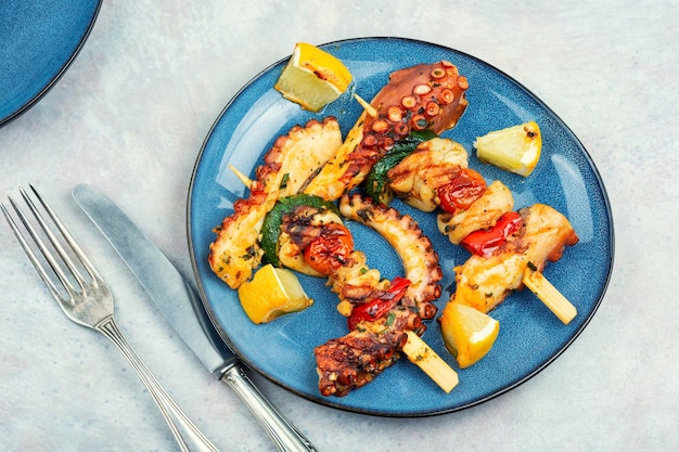 Spieße mit Oktopus und Tintenfisch auf dem Teller Gegrillter Oktopustentakel Meeresdelikatesse