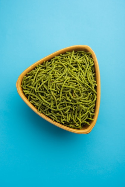 Spinat oder Palak Sev sind knusprig gebratene herzhafte Nudeln. Hausgemacht Dickes und dünnes grünes Shev oder Namkeen ist ein klassischer indischer Snack. in einer Schüssel oder einem Teller serviert