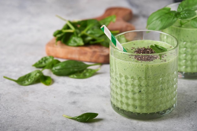 Spinat-Smoothie gesund grün Veganer Smoothie oder Milchshake aus Spinatbanane und Chiasamen auf grauem Betontischhintergrund Saubere Ernährung alkalische Ernährung Draufsicht Mock up