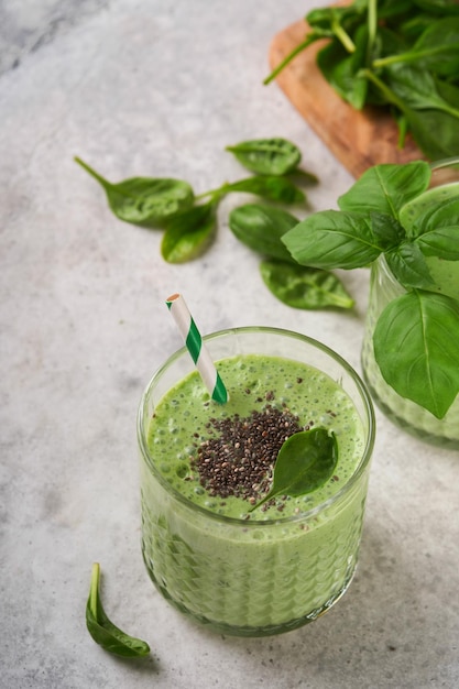 Spinat-Smoothie gesund grün Veganer Smoothie oder Milchshake aus Spinatbanane und Chiasamen auf grauem Betontischhintergrund Saubere Ernährung alkalische Ernährung Draufsicht Mock up