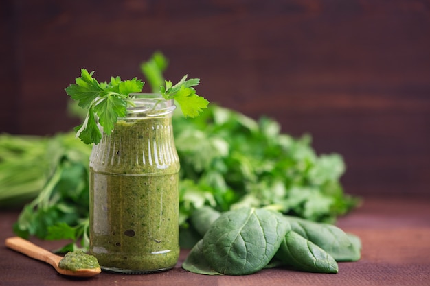 Spinat-Smoothies. Gesunder grüner Saft mit Zutaten auf dunklem Holztisch. Seitenansicht