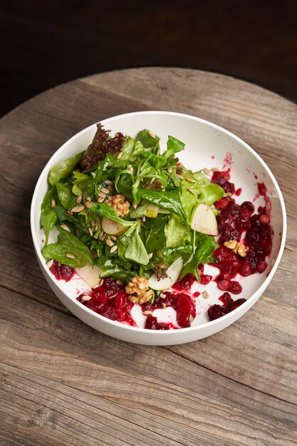 Spinatsalat in einer weißen Schüssel. Gesunder Diät-Salat mit Spinatblättern, Walnüssen, Obst und Gemüse