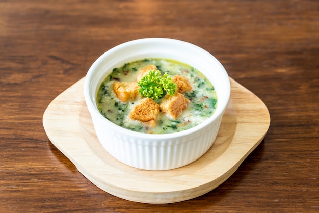 Spinatsuppe mit Brot in weißer Schüssel