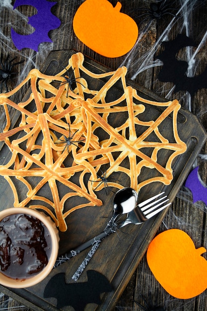 Spinnen auf hausgemachten netzförmigen Pfannkuchen für Halloween. Gruseliges Halloween. Sicht von oben. Nahaufnahme.