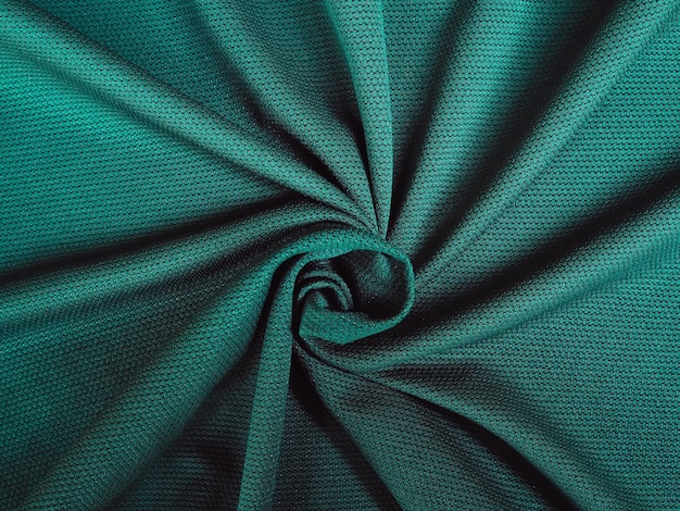 Foto spiralform aus grünem stoff. stoffstruktur aus natürlichem baumwoll-, woll-, seiden- oder leinentextilmaterial. grüner stoffhintergrund