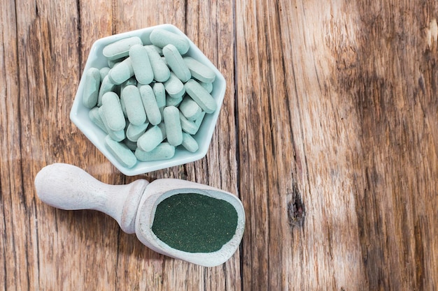 Spirulina em pó e comprimidos em fundo de madeira