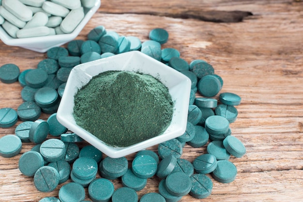 Spirulina em pó e comprimidos em fundo de madeira