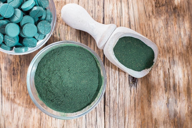 Spirulina em pó e comprimidos em fundo de madeira