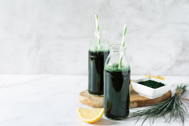 Spirulina-Getränk mit Zitronen- und Spirulina-Algenpulver auf weißem Marmortisch