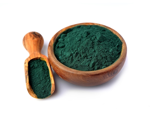 Spirulina in Schüssel und Holzlöffel isoliert